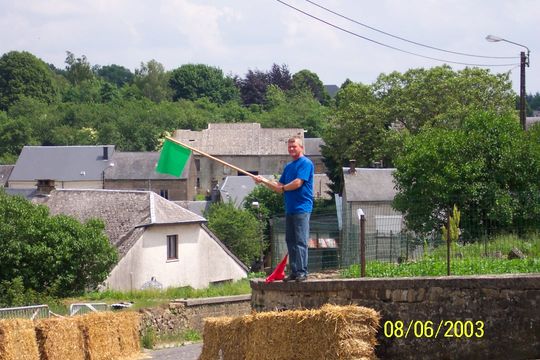 Un commissaire de course agite le drapeau vert au-dessus des bottes de paille, 2003