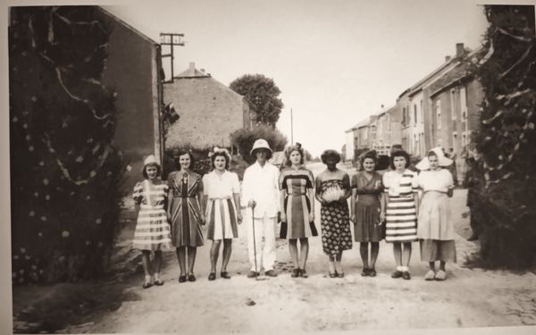 Les dames du quartier alignées au milieu de la rue, un jour de fête.