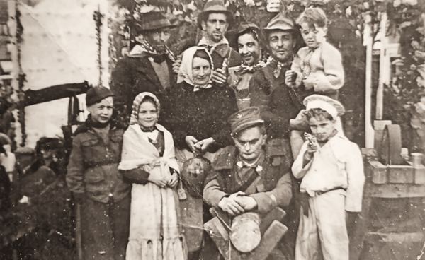 Enfants costumés et soldats sous un arc de verdure, sans doute à la libération.