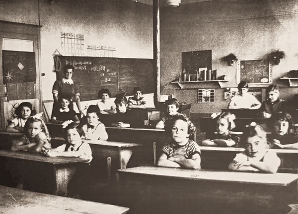 En classe, derrière les pupitres.