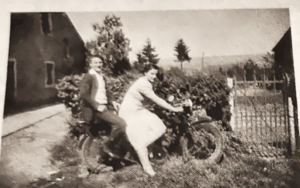 Jean et Jeanne Poncin : deux cousins aux prénoms jumeaux. La moto appartient à Fernand Bauduin. Les cousins endimanchés posent dans la rue principale devant…