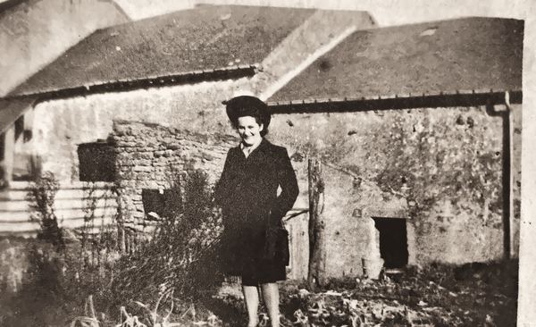 Jeanne Poncin, à l'imposant chapeau noir, derrière la maison des Bauduin. L'habitation dispose, comme la plupart des foyers, d'un verger. Une partie reçoit…